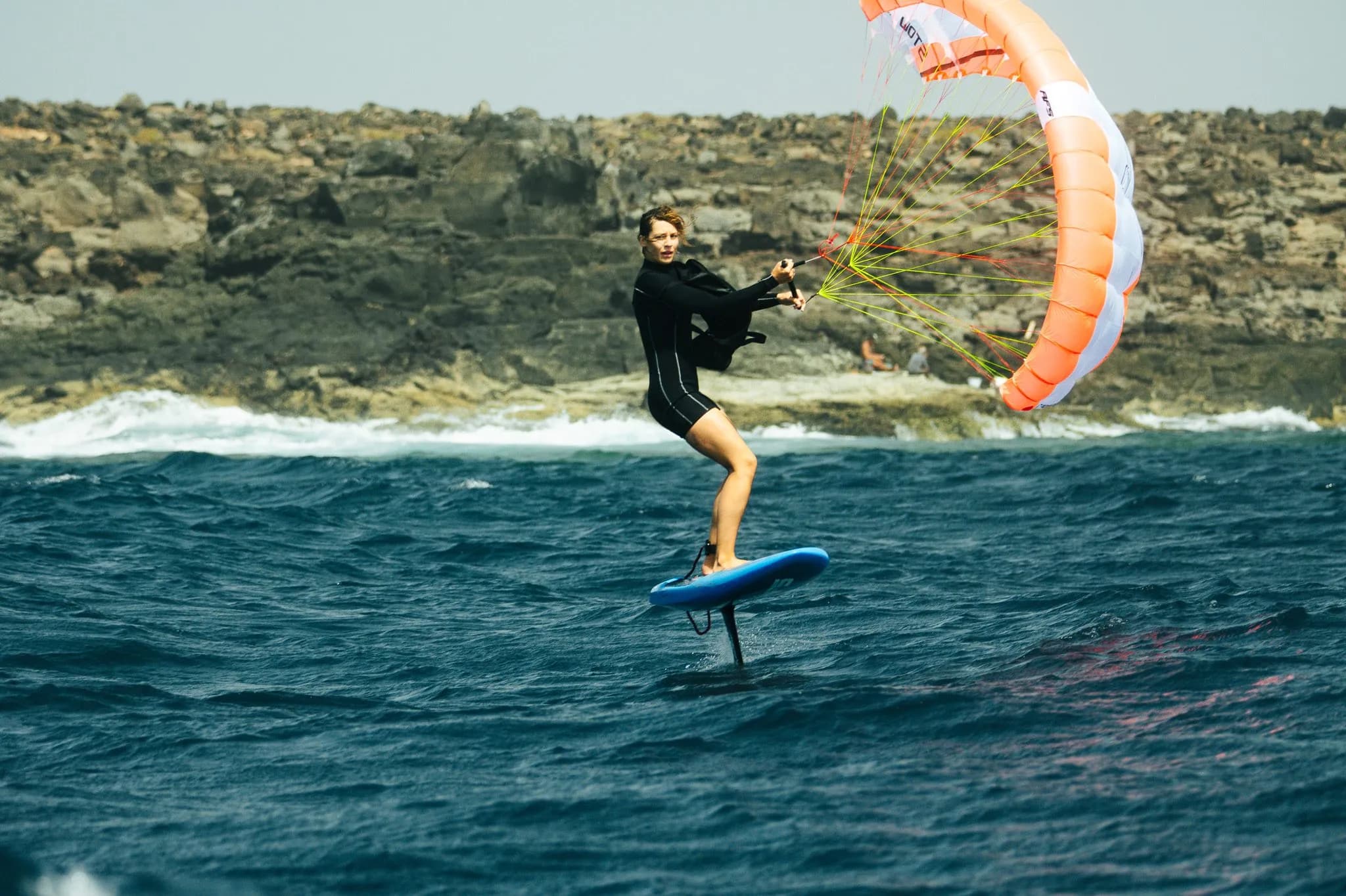 Parawing foiler riding in front of a cliff